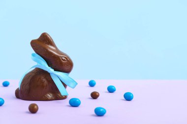 Çikolatalı Paskalya tavşanı ve renkli arka planda şekerler.