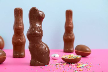 Çikolatalı Paskalya yumurtaları ve renkli arka planda tavşanlar.