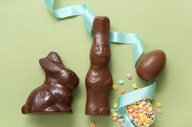 Çikolatalı Paskalya yumurtaları ve yeşil arka planda tavşanlar.