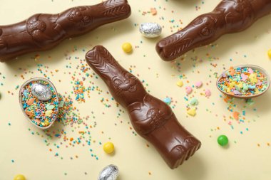 Çikolatalı Paskalya yumurtaları ve sarı arka planda tavşanlar.