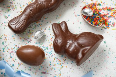 Çikolatalı Paskalya yumurtaları ve gri arka planda tavşanlar.