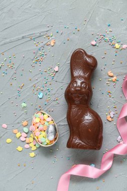 Çikolatalı Paskalya yumurtası, gri arka planda serpiştirilmiş tavşancık.