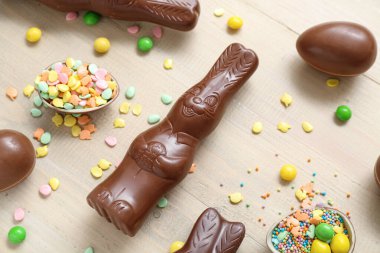 Çikolatalı Paskalya yumurtaları ve bej ahşap arka planda tavşanlar.