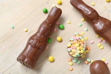 Çikolatalı Paskalya yumurtaları ve bej ahşap arka planda tavşanlar.