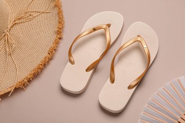 Hasır şapkalı ve fanı bej arka planda olan kadın tarzı terlikler.