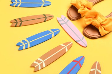 Farklı mini sörf tahtaları ve sarı arka planda kadın ayakkabıları.