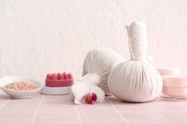 Renkli arkaplanda bitkisel masaj torbaları ve kozmetik ürünleri olan kompozisyon
