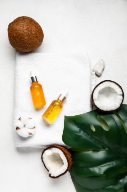 Beyaz arka planda banyo havlusuyla hindistan cevizi kozmetik yağı şişeleri.