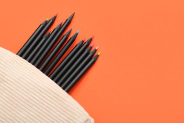 Turuncu arka planda bir sürü renkli kalemli kutu