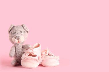 Pembe arka planda sevimli oyuncakları olan şık bebek ayakkabıları.