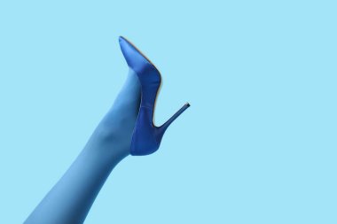 Şık mavi topuklu, arka planda genç bir kadın bacağı.