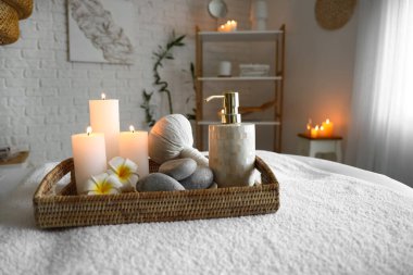 Spa composition with burning candles on couch in salon, closeup