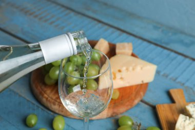 Arka planda beyaz şarap kadehe dökülüyor, yakın plan.