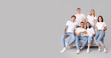 Gri arka planda şık kotlu ve metin için yeri olan bir grup genç.