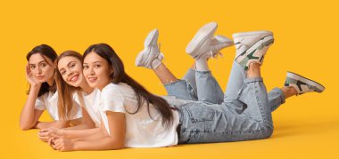 Sarı arka planda şık kotlu bir grup genç kadın.