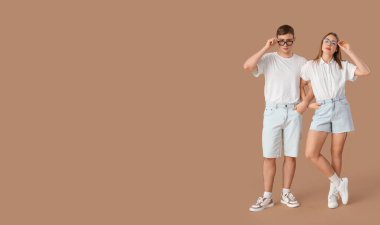 Bej arkaplanlı şık kot şortlu genç çift, mesaj için yer var.