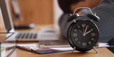 Ofisteki yorgun işadamlarının masasındaki çalar saat. Zaman yönetimi kavramı