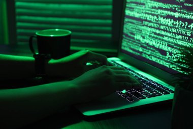 Kadın programcı gece ofiste dizüstü bilgisayarda daktilo kullanıyor.