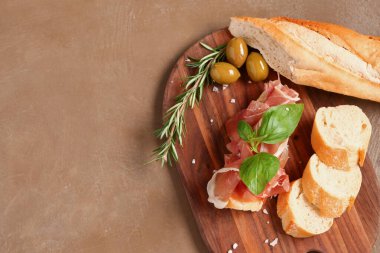 Tahta tahtada jambonlu lezzetli sandviç ve kahverengi arka planda ekmek.