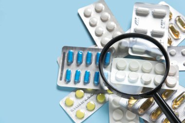 Mavi arka planda farklı haplar içeren büyüteç