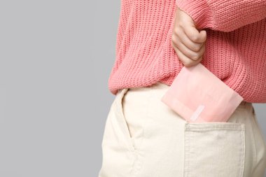 Gri arka planda regl pedi olan güzel bir genç kadın. Yakın plan.