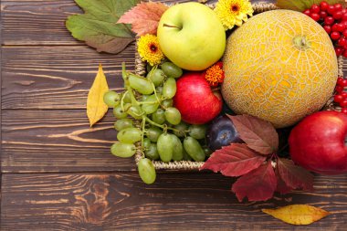 Tahta arka planda farklı taze meyvelerle dolu sepet.