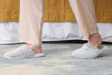 Yatak odasında dinlenen yumuşak terlikli genç bir kadın.