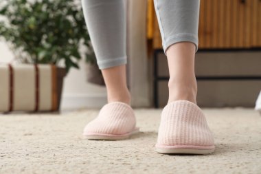 Evde yumuşak terlikli genç bir kadın, yakın plan.