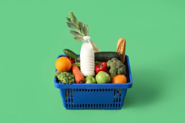 Yeşil arka planda yiyecek dolu alışveriş sepeti