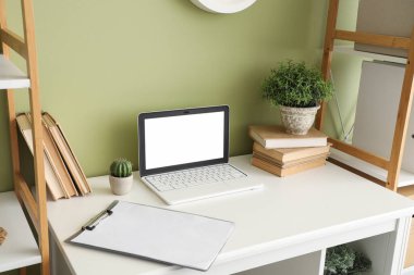 Ofisinde kitaplar ve bitkiler olan boş bir laptop.