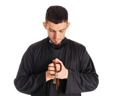 Beyaz arka planda tespih çeken genç bir rahip.