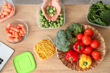Tahta masada taze ve donmuş sebzeli kadın elleri.