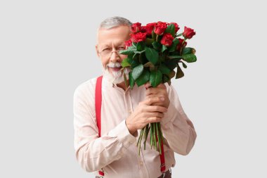 Beyaz arka planda Sevgililer Günü için gül buketi taşıyan olgun bir adam.