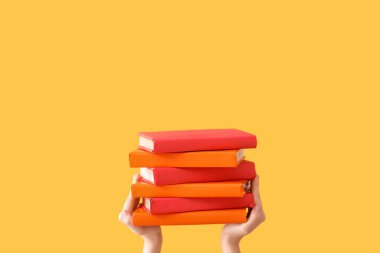 Sarı arka planda kitapları tutan eller