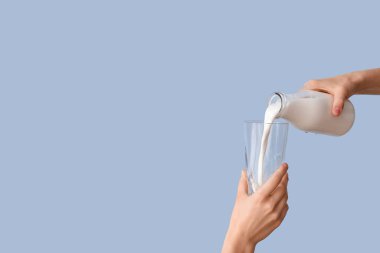 Eller sütü açık mavi arkaplanda bardaklara döküyor.