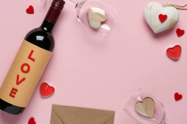 Frame made of bottle with wine, glasses and hearts on pink background. Valentine's Day celebration
