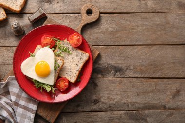 Ahşap zemin üzerinde lezzetli yumurta, tost, domates ve roka tabağı.