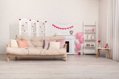 Beyaz kanepeli, şömineli ve Sevgililer Günü kutlaması için dekorlu festival salonu.