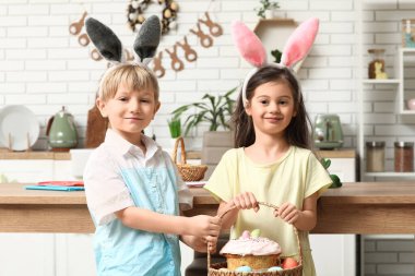 Evde paskalya yumurtası ve pastasıyla tavşan kulaklı şirin çocuklar.