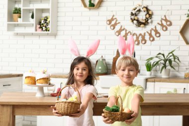 Evde paskalya yumurtası dolu sepetleri olan tavşan kulaklı şirin çocuklar.