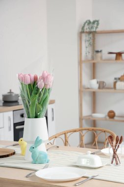 Mutfaktaki yemek masasında vazo, lale ve Paskalya tavşanı.