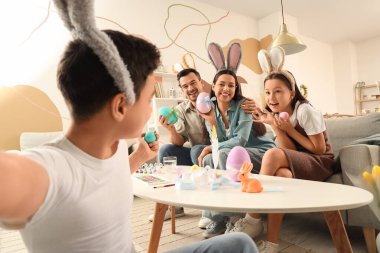Mutlu bir aile ve boyanmış yumurtalar Paskalya günü evde selfie çekiyorlar.