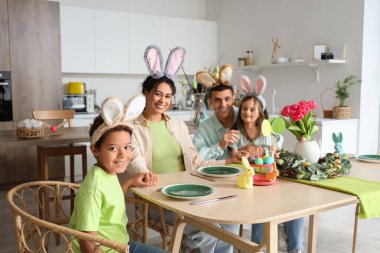 Mutlu bir aile Paskalya günü mutfakta yemek masasında oturuyor.