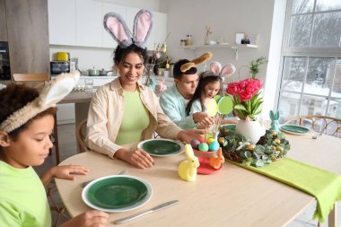 Mutlu bir aile Paskalya günü mutfakta yemek masasında oturuyor.