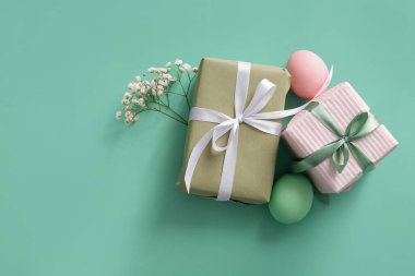 Çingene çiçekli Paskalya yumurtaları ve turkuaz arka planda hediye kutuları.