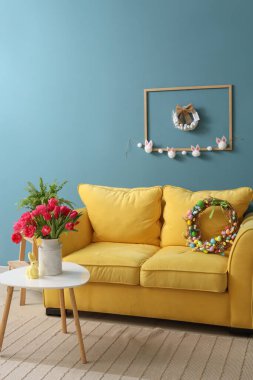 Paskalya çelengi, kanepesi ve masası olan bir oturma odası.