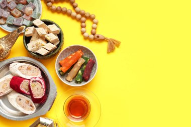 Sarı arka planda geleneksel Doğu tatlıları ve Ramazan için tasbih kompozisyonu