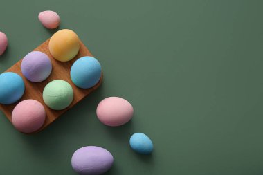 Yeşil arka planda boyanmış Paskalya yumurtaları olan tahta tutucu.