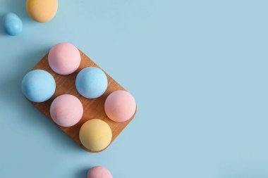 Mavi arka planda boyanmış Paskalya yumurtaları olan tahta tutucu.