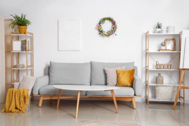 Paskalya çelengi, raf ünitesi ve kanepesi olan oturma odasının içinde.